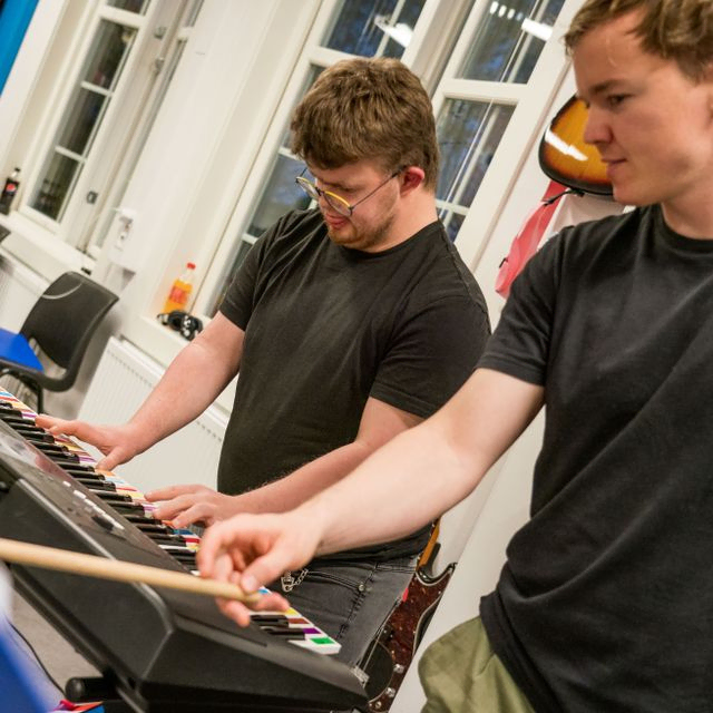 En instruktør peker ut noter fra fargenotasjonsark for en som spiller keyboard