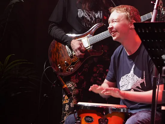 Elev som smiler og spiller trommer på en scene