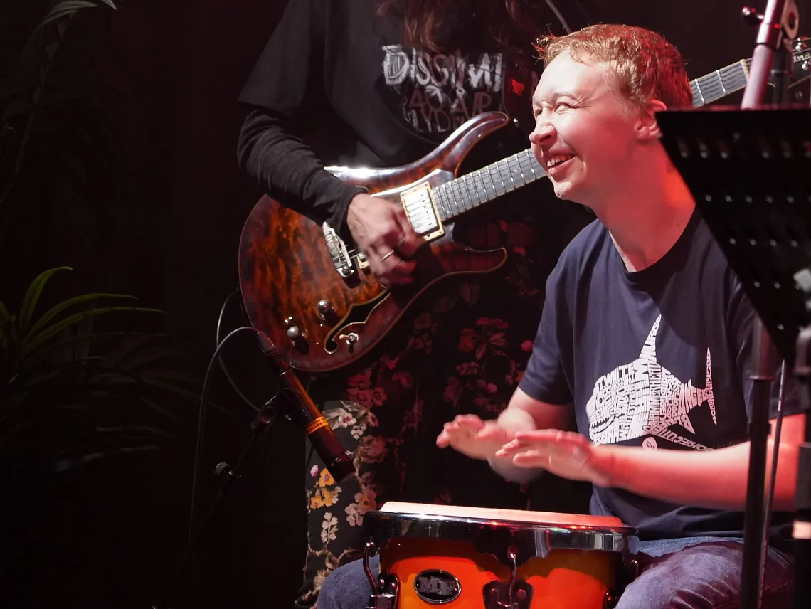 Elev som smiler og spiller trommer på en scene