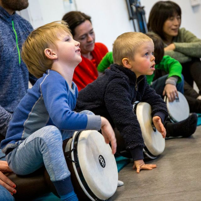 barn og voksne spiller på tromme