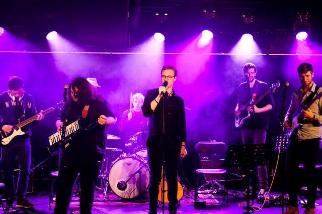 Band med 6 medlemmer på scenen med lilla lys