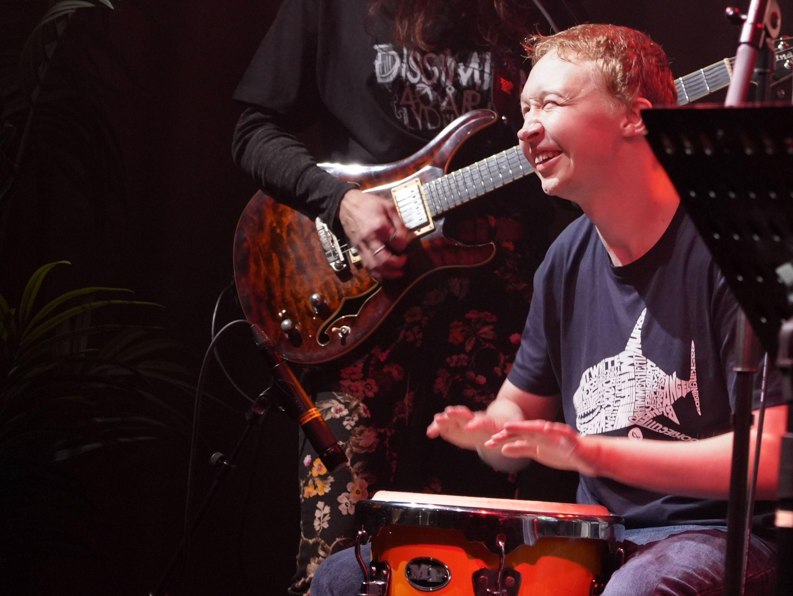 Elev som smiler og spiller trommer på en scene